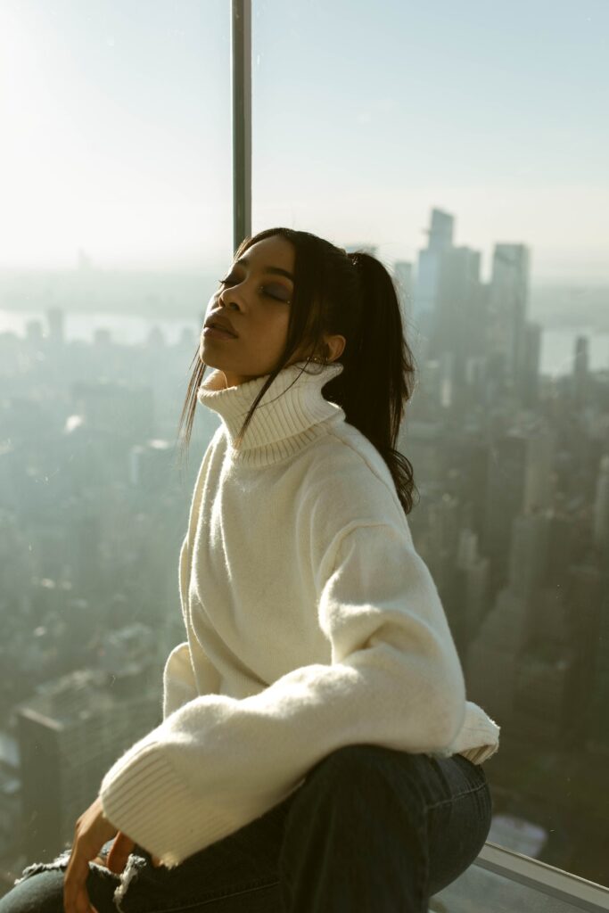 woman-in-oversized-sweater sitting on observation tower in new york