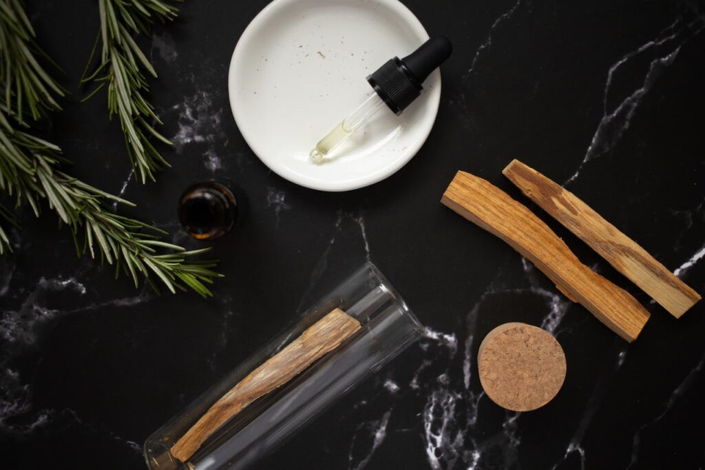 glass pipette with aromatic oil in plate near rosemary branches