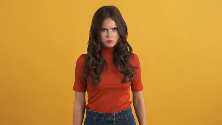 angry moody brunette girl red top aggressively looking camera colorful background