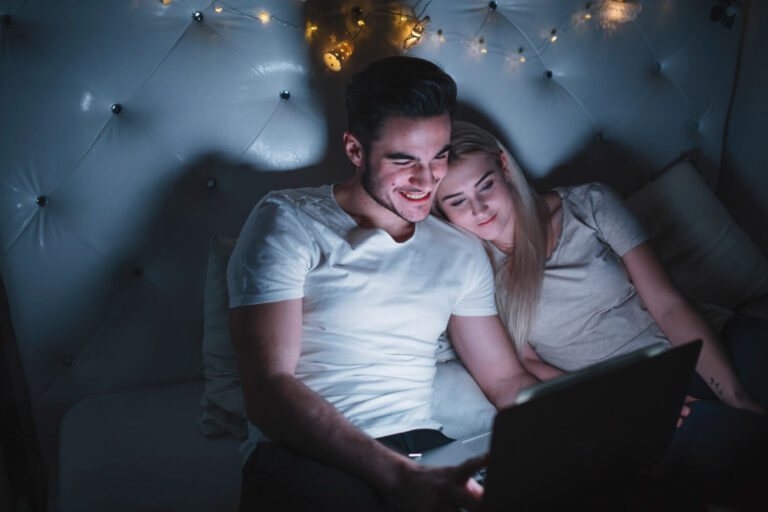 cheerful couple watching movie bed