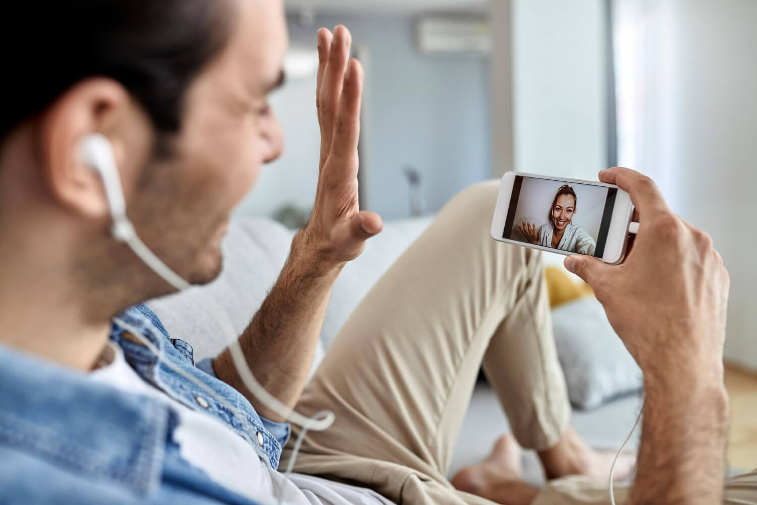 closeup man using mobile phone waving while having video chat with his girlfriend
