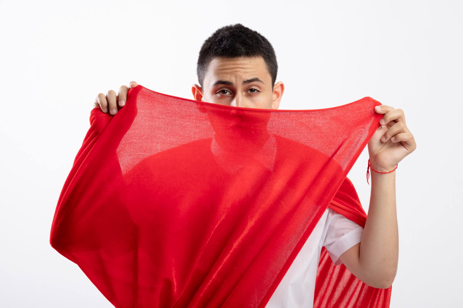 confident young superhero boy red cape grabbing cape looking front from it isolated white wall