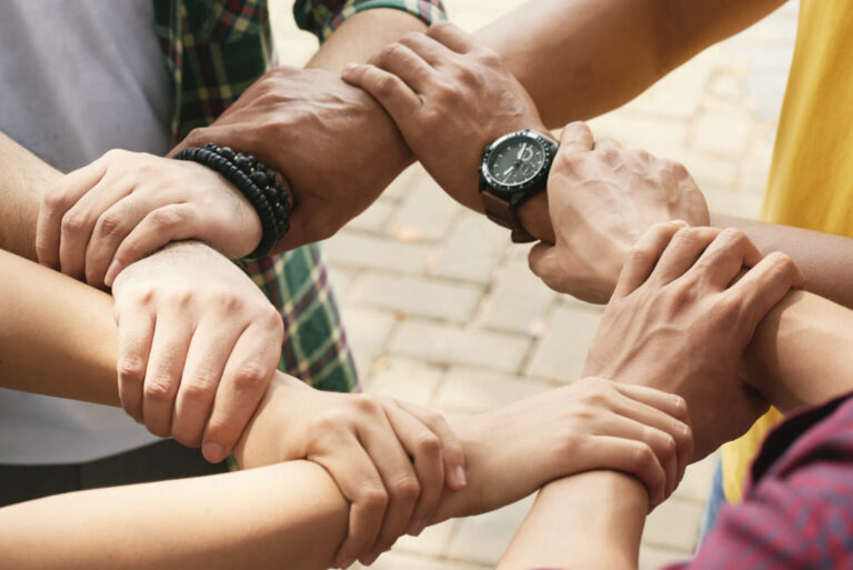 cropped friends holding wrists each other chain support collaborate