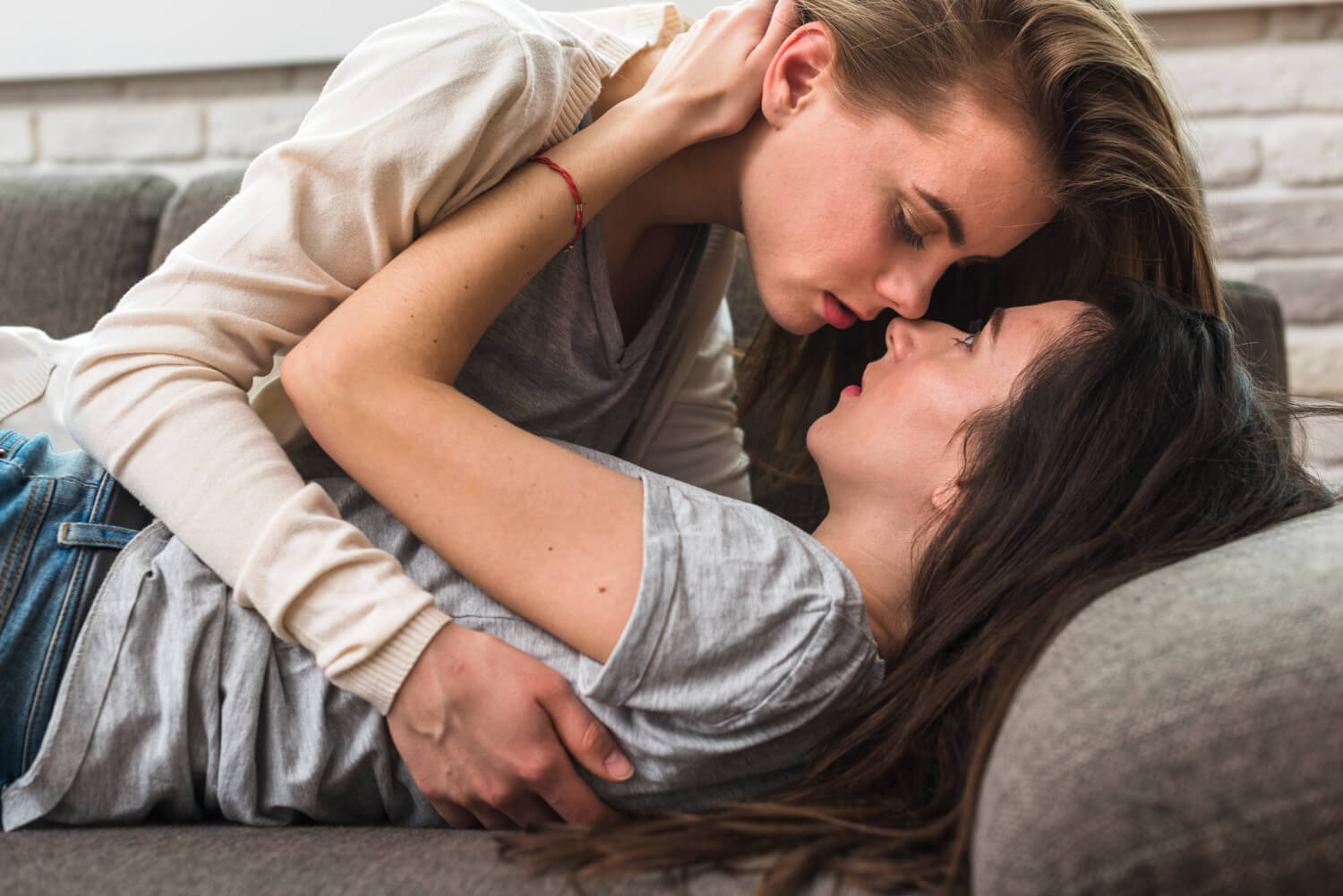 passionate lesbian young couple loving each other grey sofa