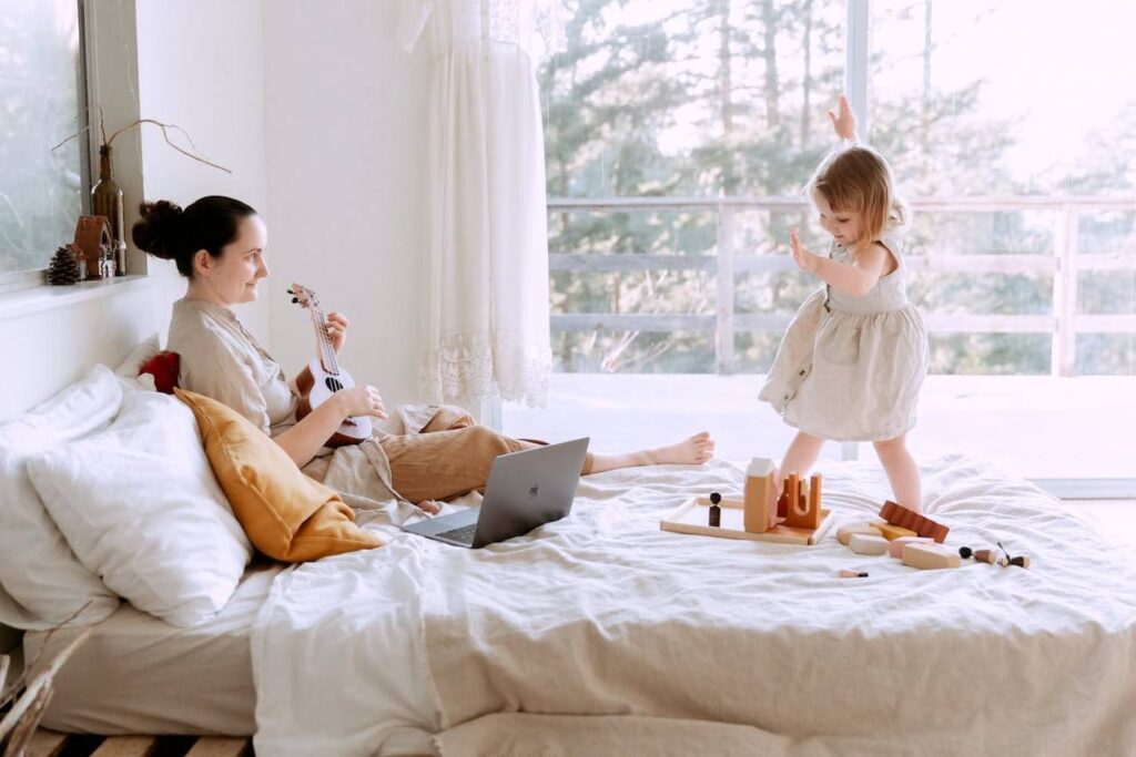 happy young woman-playing ukulele for daughter at home