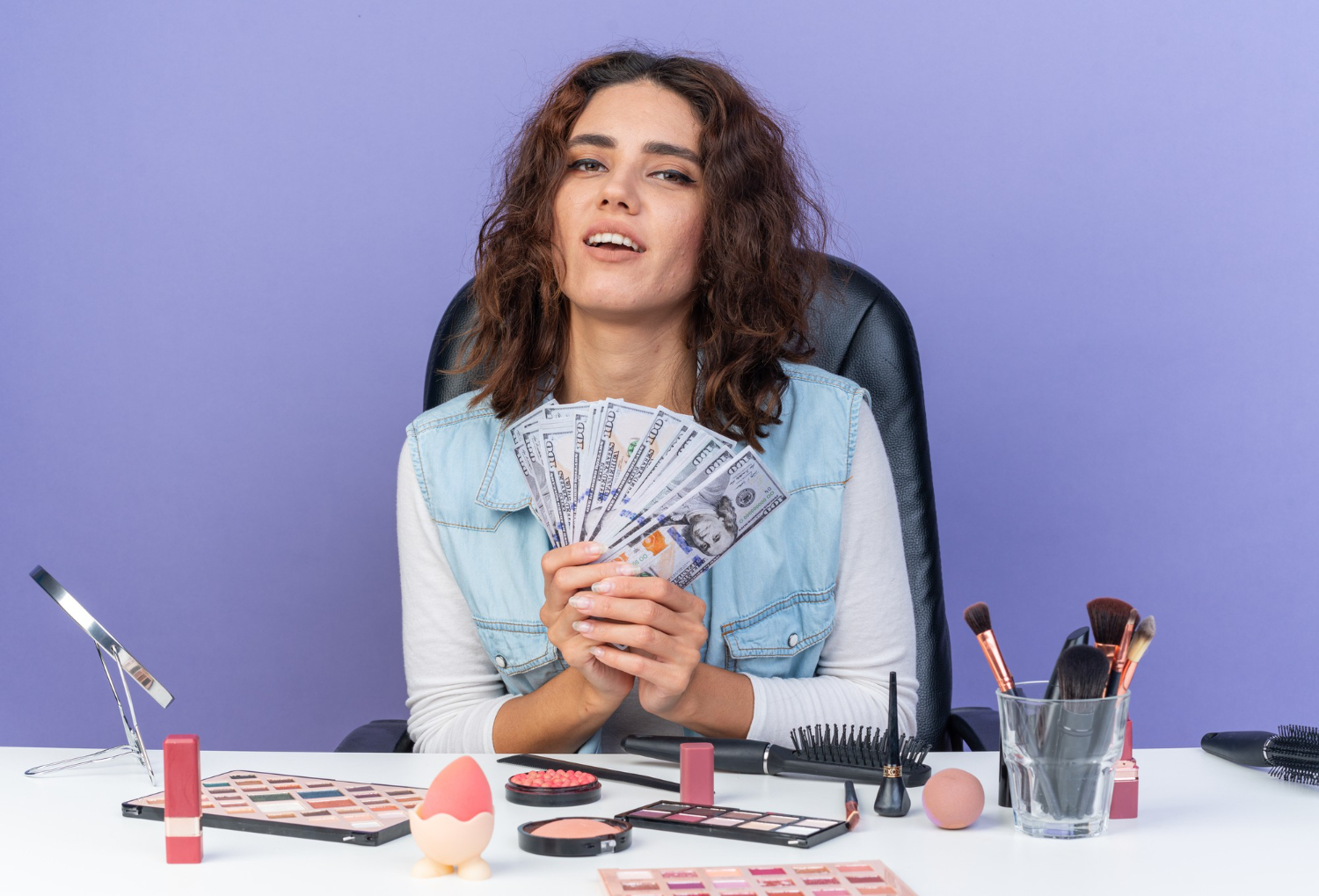 pleased pretty Caucasia woman sitting table with makeup tools holding money