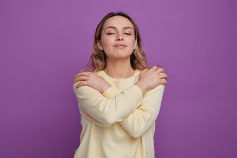 pleased young girl embracing herself with closed eyes