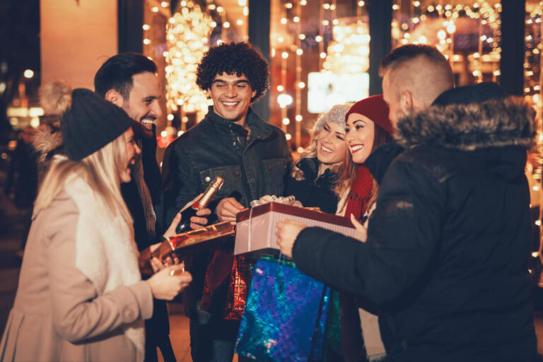 six beautiful young people having fun while buying some presents smiling holding many shopping paper bags boxes town street