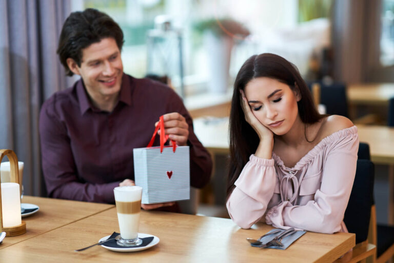 young couple valentines day strict guy covered girl eyes with hand showing silence gesture isolated orange background