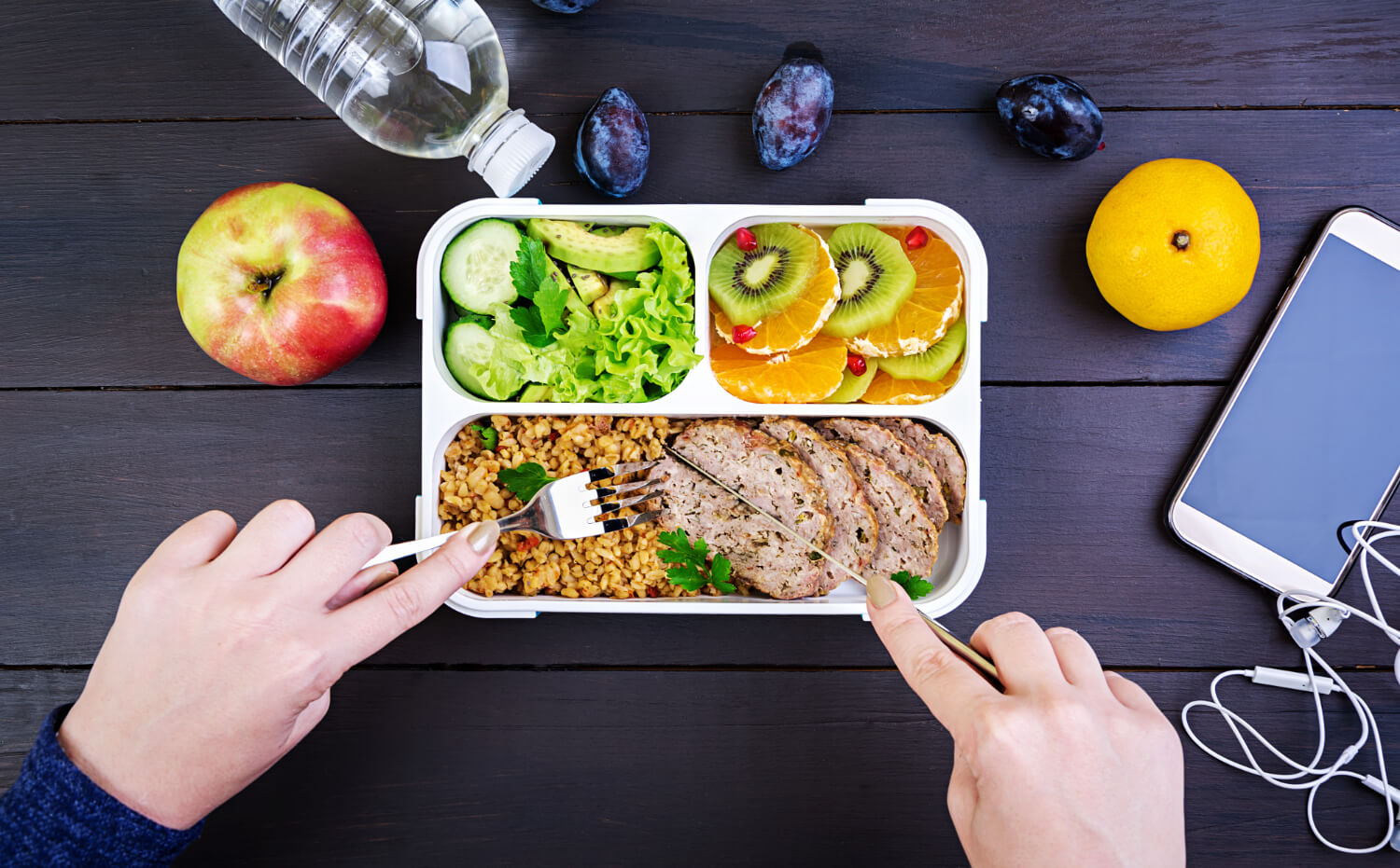 top view showing hands eating healthy lunch with bulgur meat fresh vegetables fruit wooden table fitness healthy lifestyle concept lunchbox top view