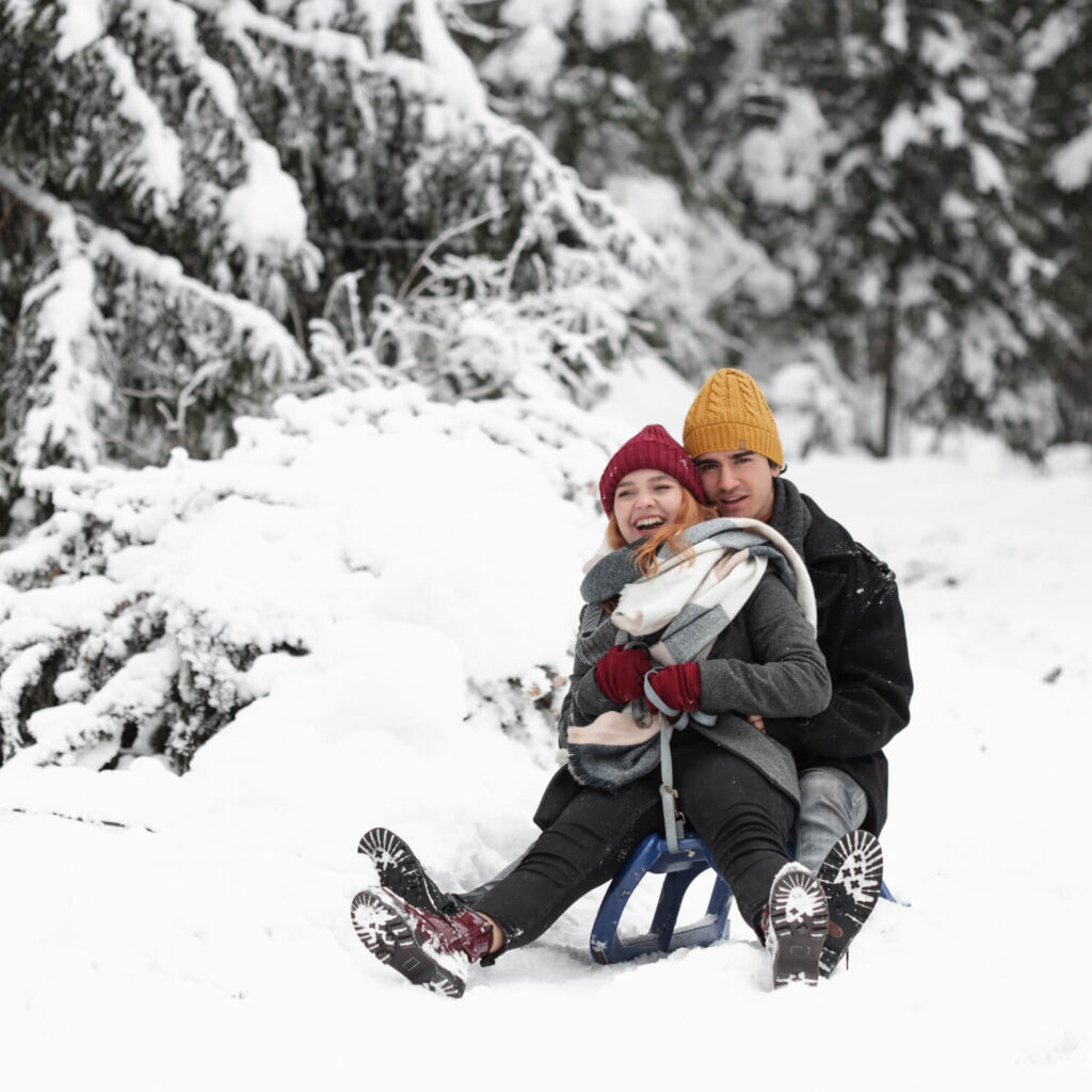 young beautiful couple having fun sitting sleigh