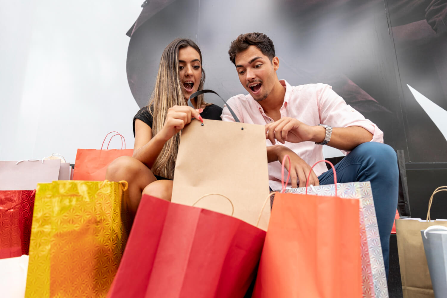 amazed young couple looking inside shopping bags