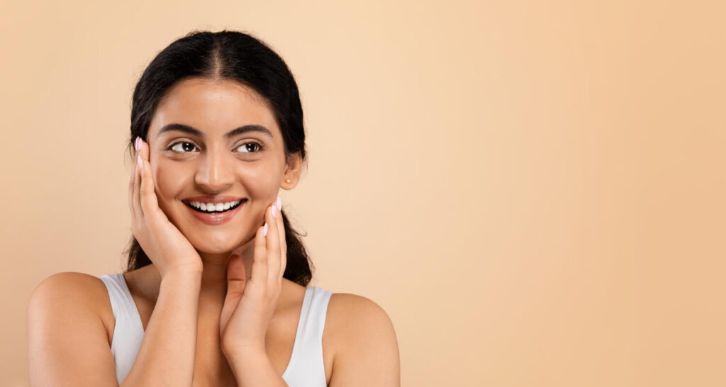 beautiful young indian woman looking aside copy space touching face