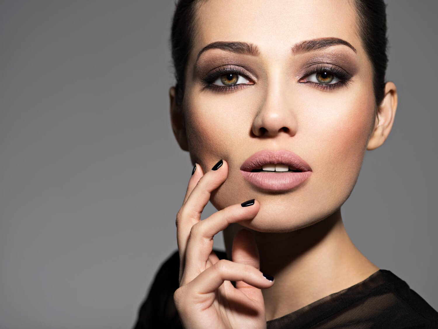 face beautiful girl with fashion makeup black nails posing dark wall