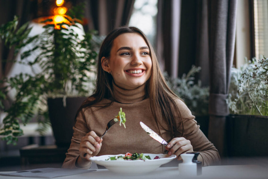 young woman eating salad cafe