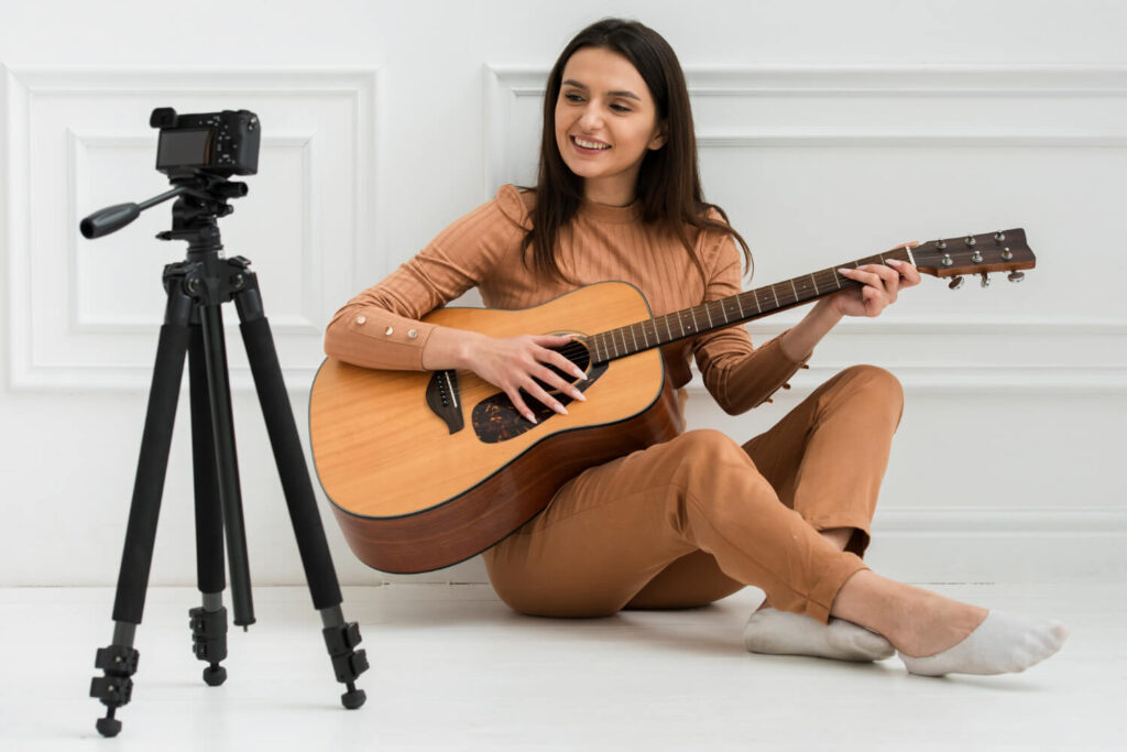 a girl playing guitar in front of camera