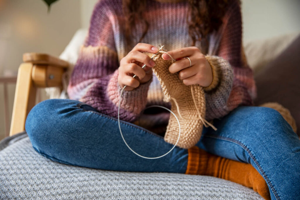 close up woman knitting home