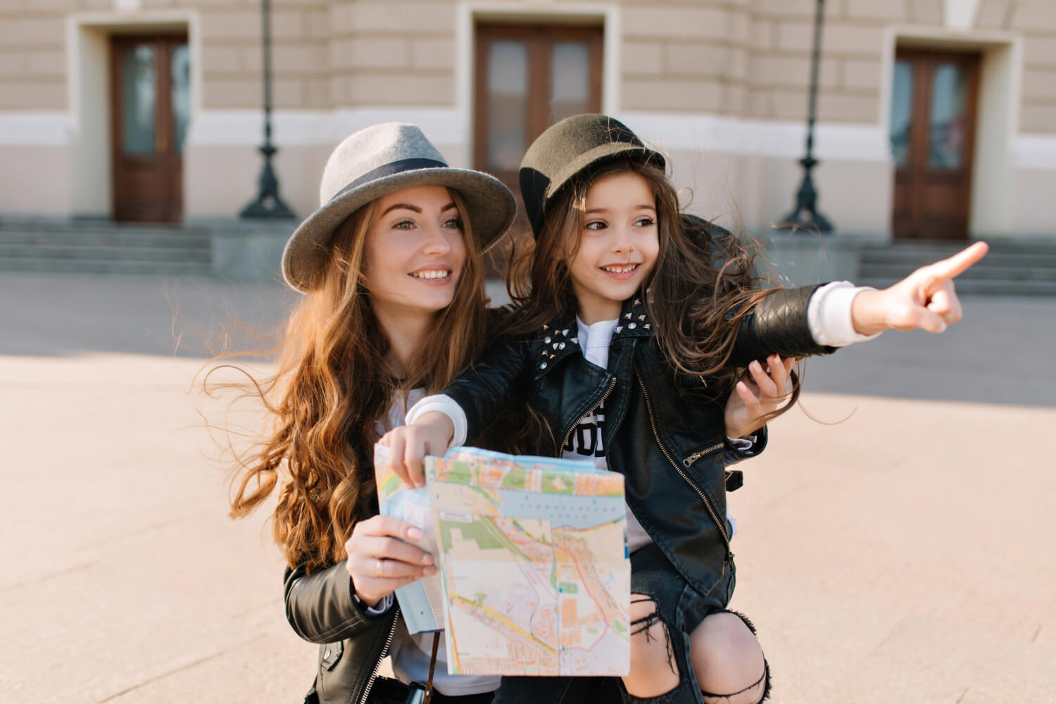 portrait adorable little girl trendy hat pointing with finger sights new city travel with mom charming woman carrying cheerful daughter holding map looking around with smile