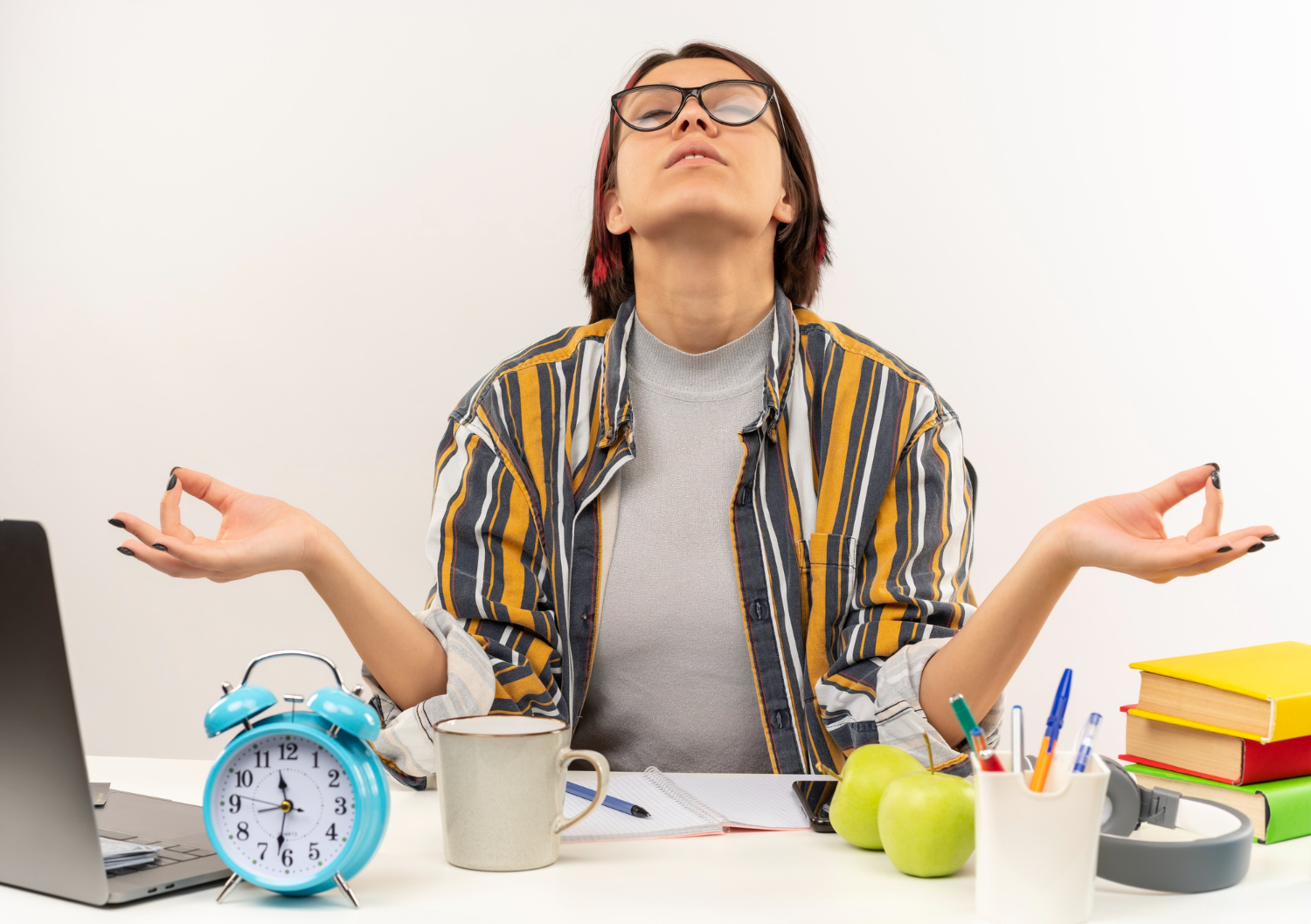 peaceful young student girl wearing glasses sitting desk meditating with closed eyes isolated white background