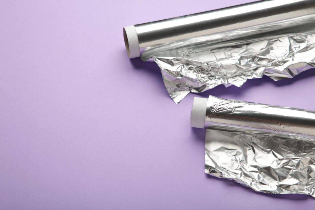 roll aluminum foil purple background space text