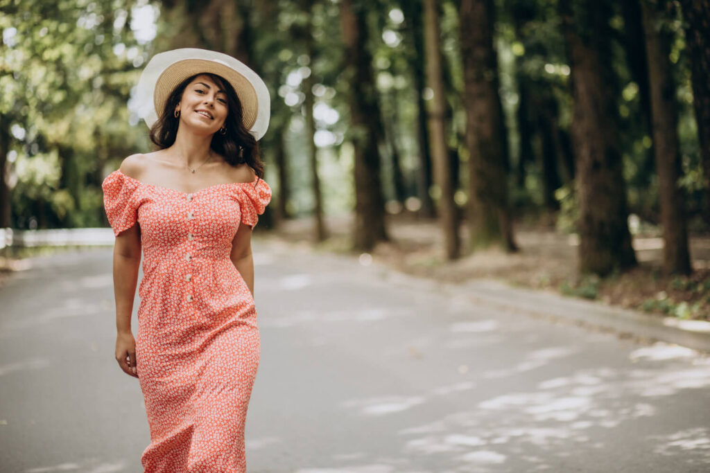 young woman wearing dress hat walking park