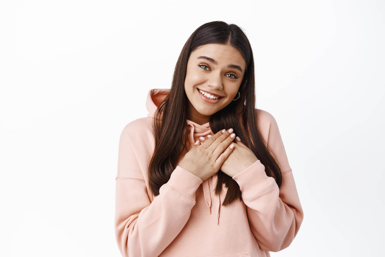 cute heartfelt girl receive gift holding hands heart smiling pleased say thank you express gratitude standing hoodie against white wall