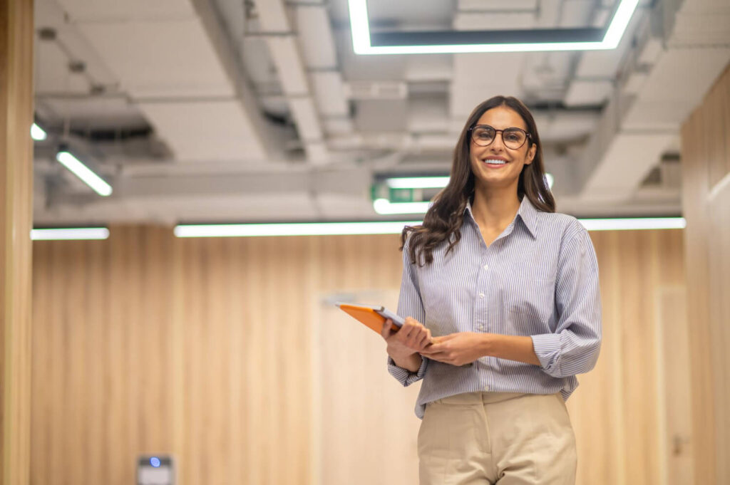 woman with folder smiling camera indoors