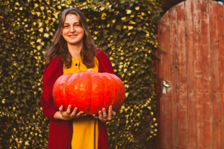 portrait smiling young woman standing by pumpkin