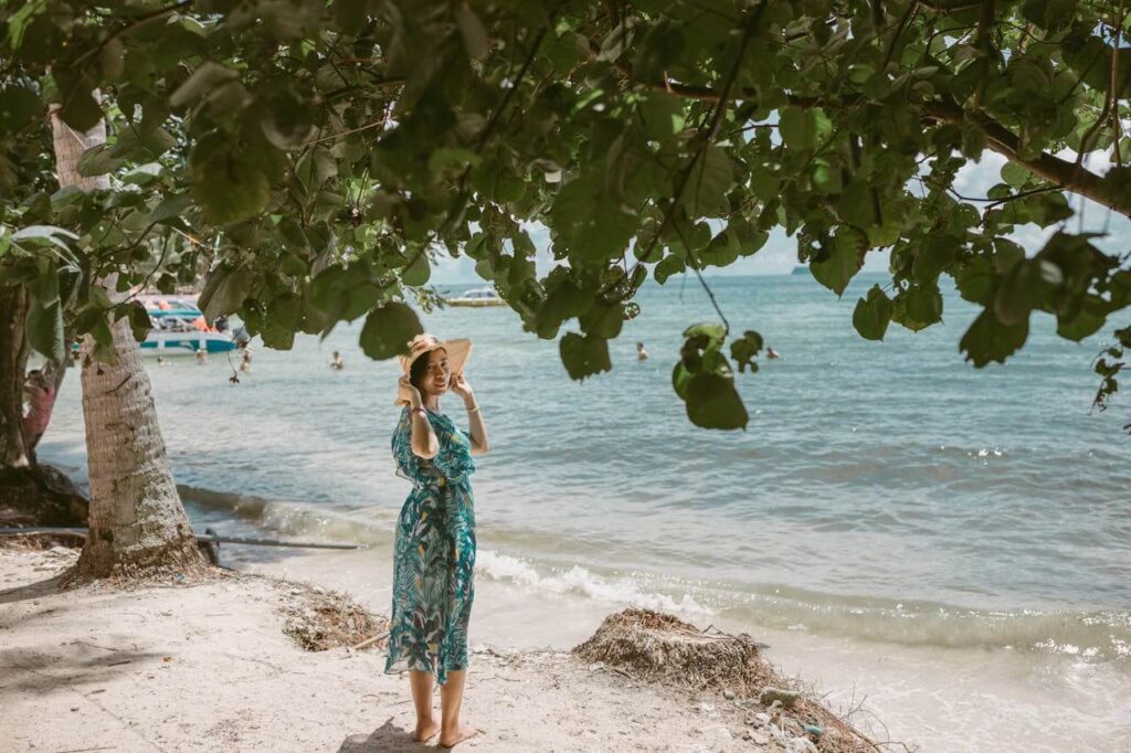 woman in hat and sundress standing on beach